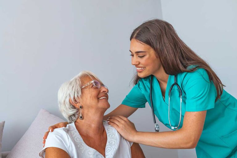 Volunteer chatting with an older resident in a bright assisted living common room.